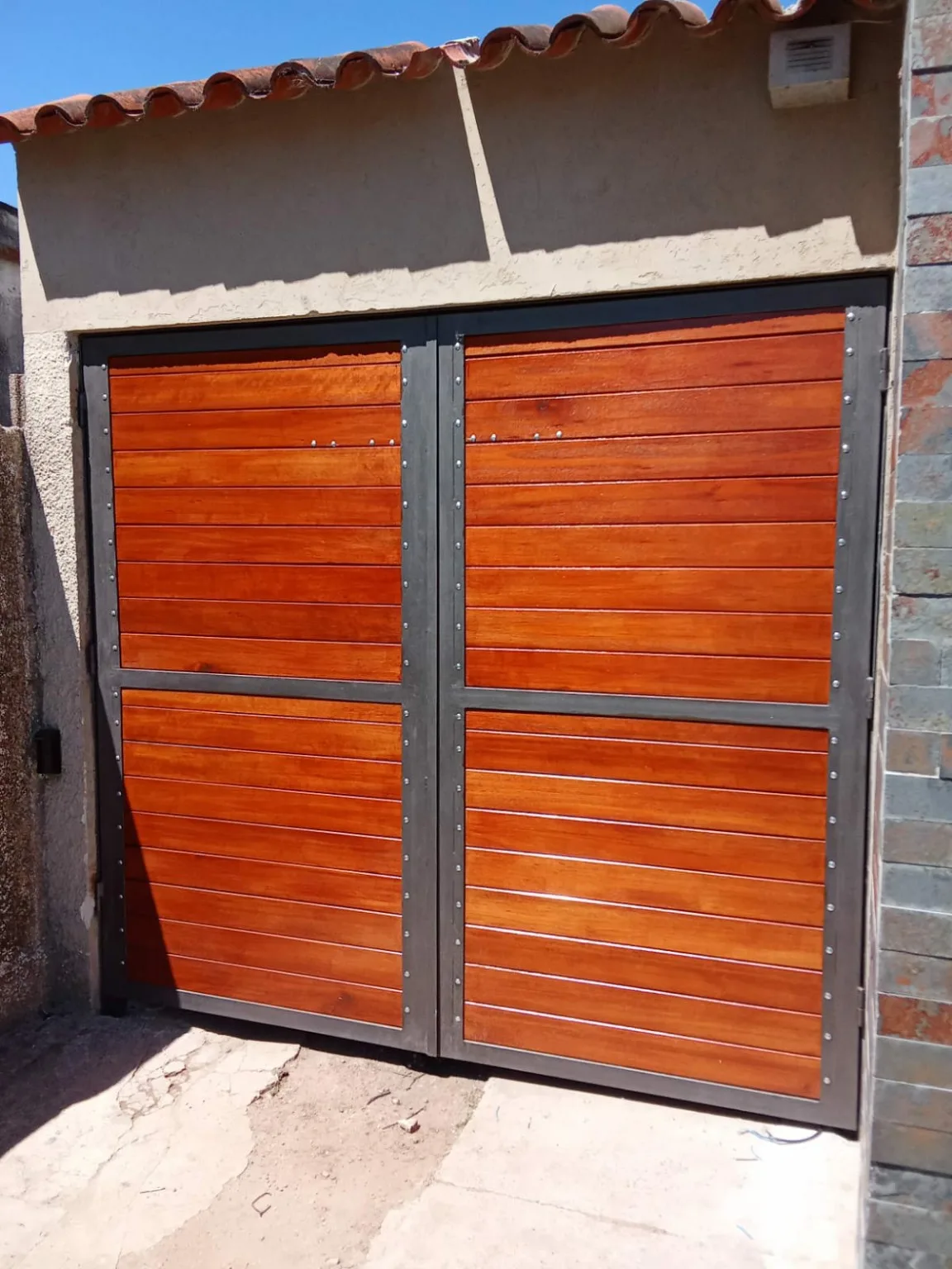 Portón de dos hojas con madera y estructura metálica
